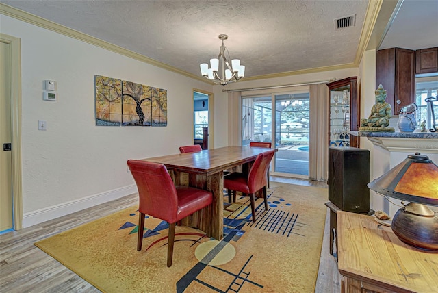 dining area with ornamental molding, a textured ceiling, an inviting chandelier, and light hardwood / wood-style floors