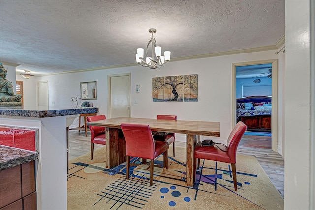 dining room featuring an inviting chandelier, ornamental molding, a textured ceiling, and light hardwood / wood-style flooring