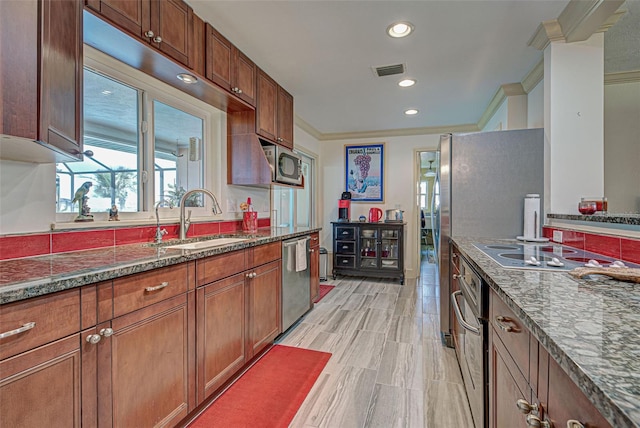 kitchen with stainless steel appliances, ornamental molding, sink, and dark stone counters