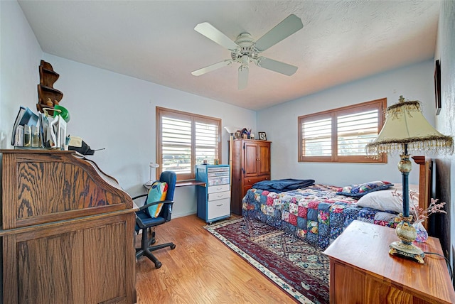 bedroom with multiple windows, light hardwood / wood-style floors, and ceiling fan