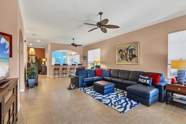 tiled living room with crown molding and ceiling fan