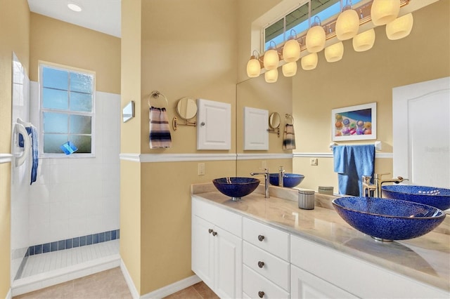 bathroom with tiled shower, vanity, and tile patterned flooring