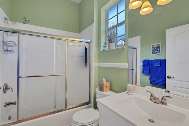 full bathroom featuring vanity, bath / shower combo with glass door, and toilet