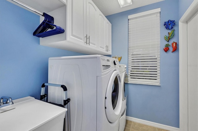 laundry area with light tile patterned floors, sink, washing machine and dryer, and cabinets