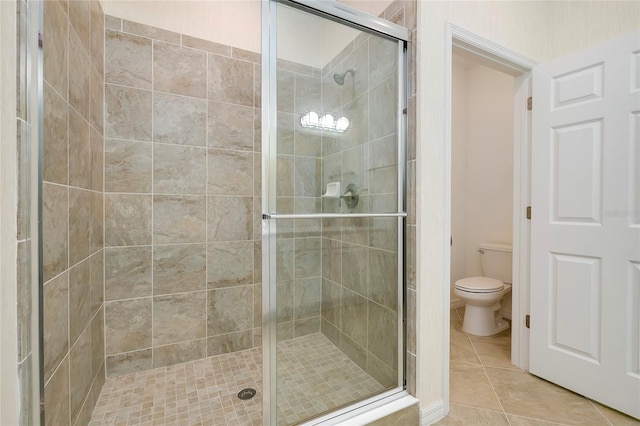 bathroom with a shower with door, tile patterned flooring, and toilet