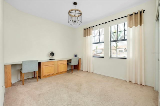 office with a chandelier, built in desk, and light carpet