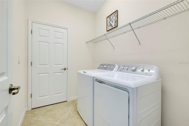 clothes washing area with light tile patterned floors and washer and clothes dryer