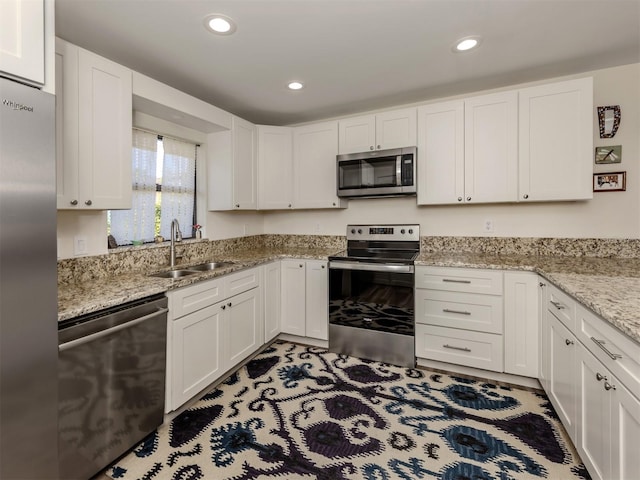 kitchen featuring light stone countertops, white cabinetry, appliances with stainless steel finishes, and sink