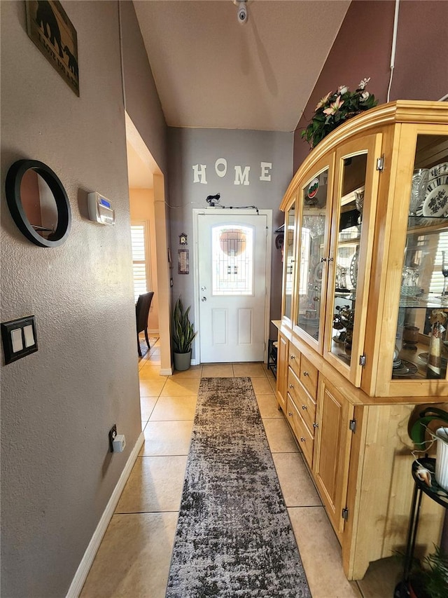 doorway to outside featuring vaulted ceiling and light tile patterned floors