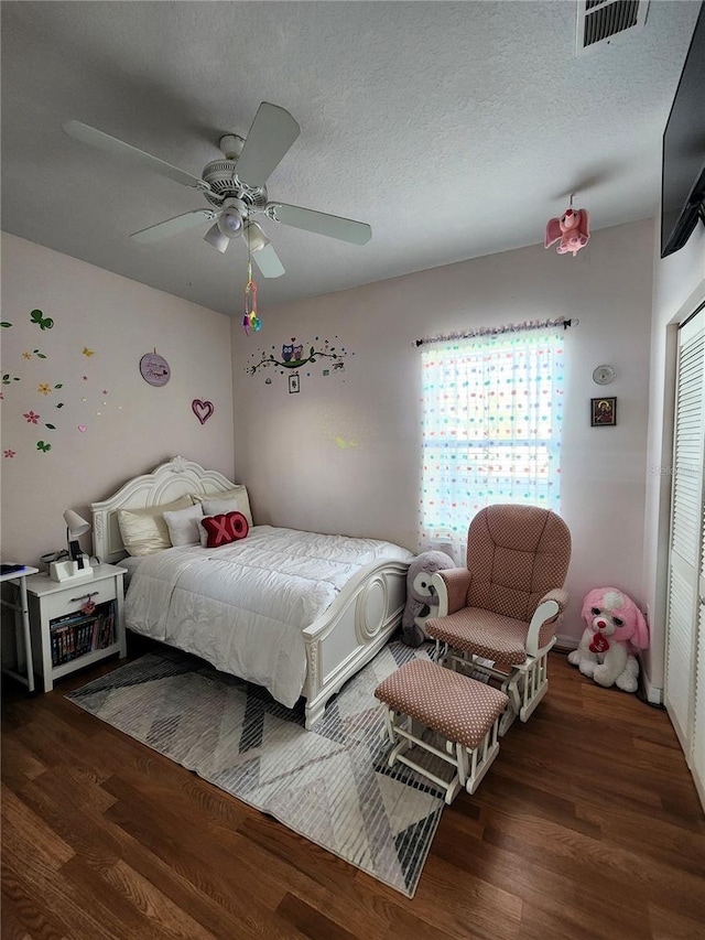 bedroom featuring dark hardwood / wood-style flooring, a textured ceiling, ceiling fan, and a closet