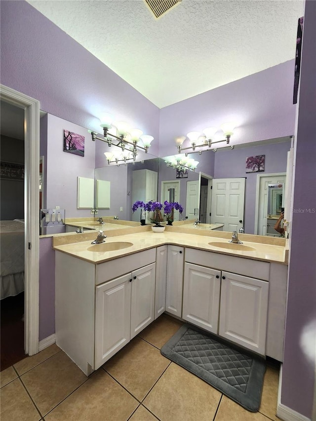 bathroom with tile patterned flooring, vanity, and a textured ceiling