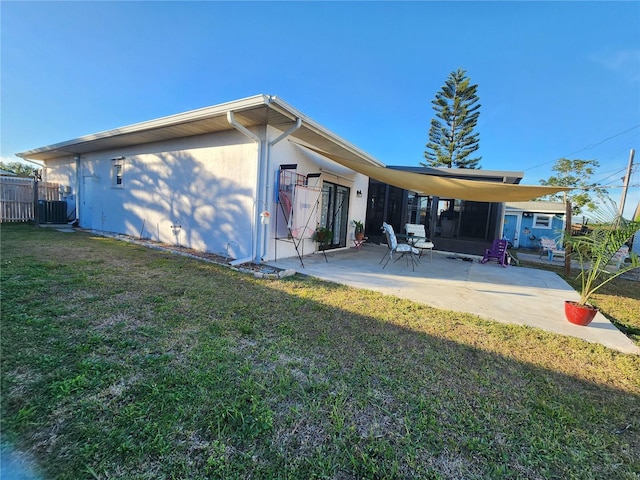 rear view of house with cooling unit, a patio area, and a lawn