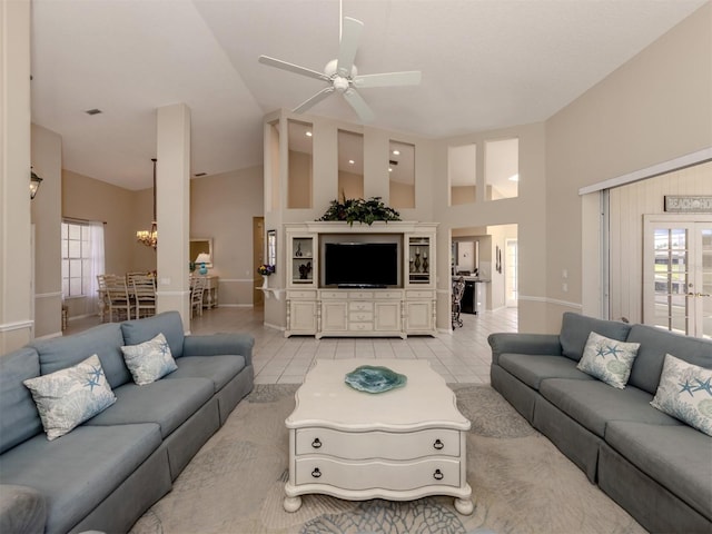 living room featuring light tile patterned flooring, plenty of natural light, ceiling fan with notable chandelier, and high vaulted ceiling