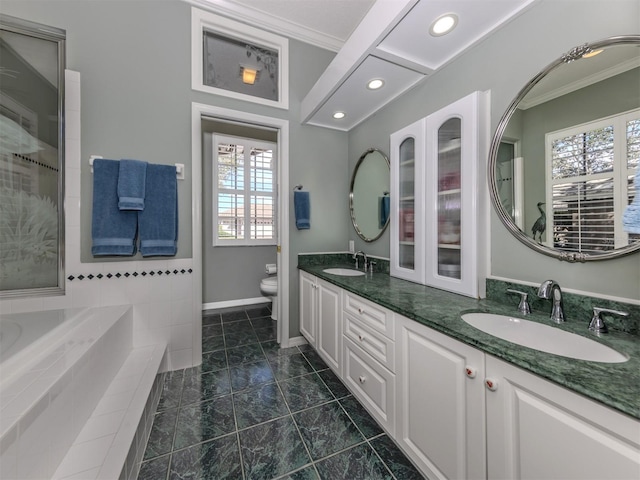 bathroom featuring crown molding, a relaxing tiled tub, vanity, and toilet