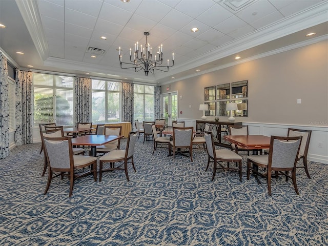 dining room with ornamental molding, a tray ceiling, dark carpet, and a notable chandelier