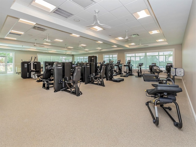 workout area with a raised ceiling, a paneled ceiling, and a wealth of natural light