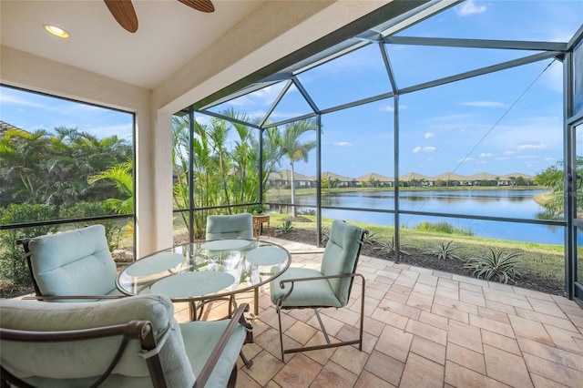 sunroom featuring ceiling fan and a water view