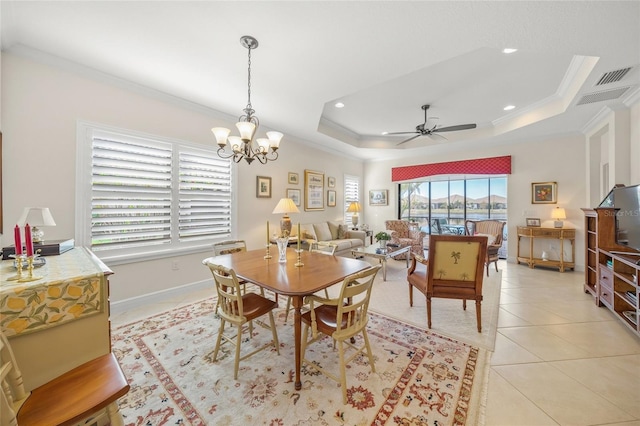 dining room featuring a raised ceiling, crown molding, ceiling fan with notable chandelier, and light tile patterned floors