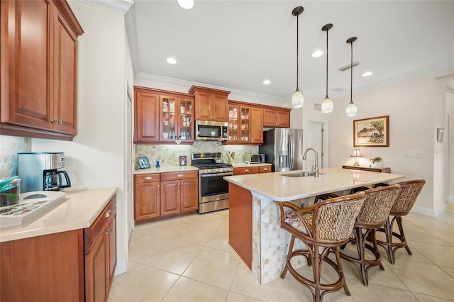 kitchen with a breakfast bar, sink, an island with sink, pendant lighting, and stainless steel appliances