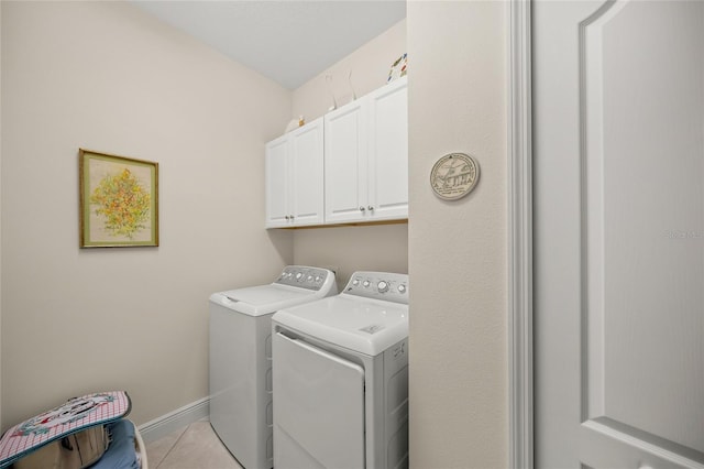 laundry area with cabinets, light tile patterned floors, and washer and dryer