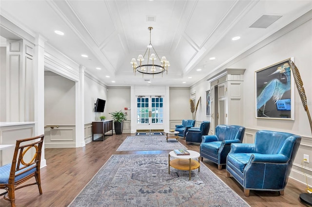 living room with an inviting chandelier, ornamental molding, coffered ceiling, and wood-type flooring