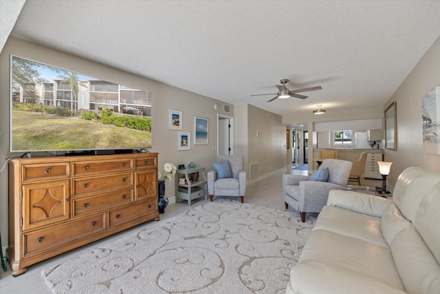 carpeted living room featuring ceiling fan and a textured ceiling