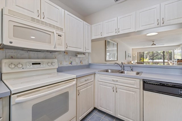 kitchen with sink, white appliances, dark tile patterned floors, ceiling fan, and white cabinetry