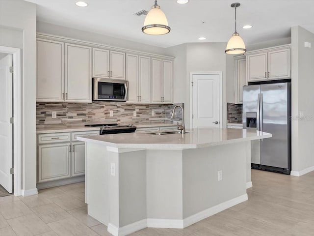 kitchen with stainless steel appliances, hanging light fixtures, sink, and a center island with sink