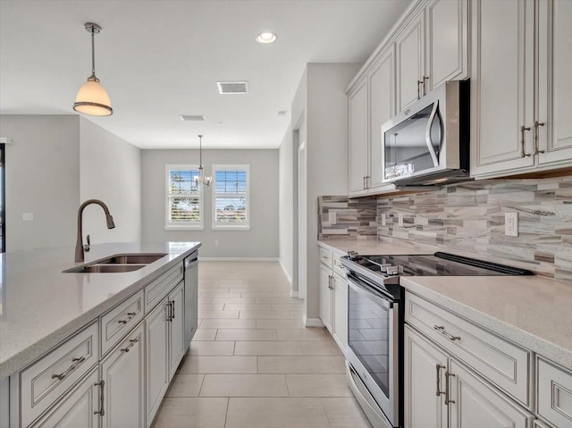 kitchen with pendant lighting, appliances with stainless steel finishes, sink, and white cabinets