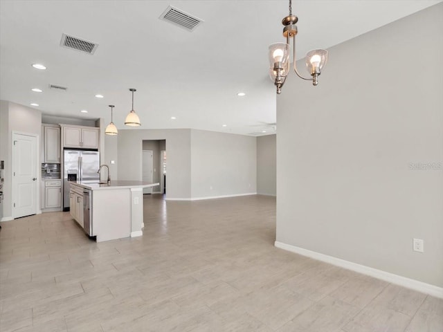 kitchen with pendant lighting, sink, a kitchen island with sink, and a notable chandelier