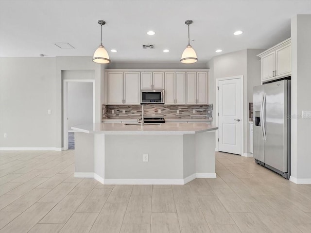 kitchen featuring hanging light fixtures, backsplash, stainless steel appliances, and a center island with sink