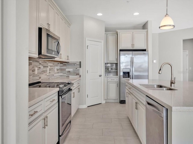 kitchen featuring sink, appliances with stainless steel finishes, a kitchen island with sink, white cabinets, and decorative light fixtures