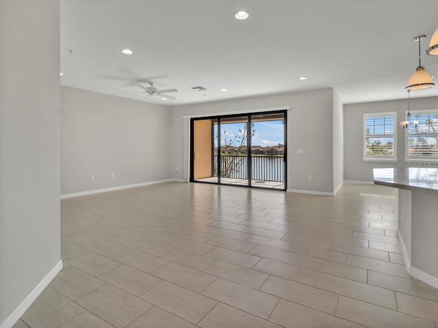 unfurnished room with ceiling fan with notable chandelier