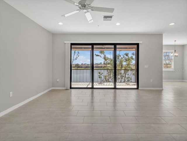 unfurnished room featuring ceiling fan with notable chandelier and a water view