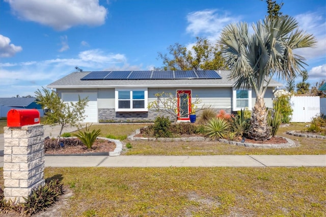 view of front facade featuring a garage, a front lawn, and solar panels