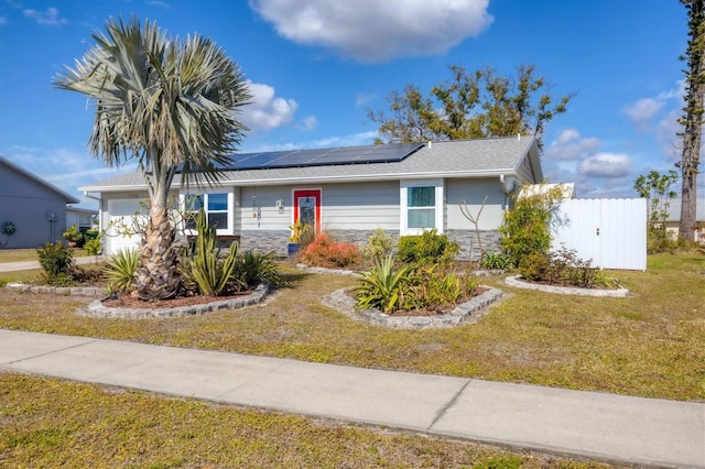 single story home featuring a garage, a front lawn, and solar panels