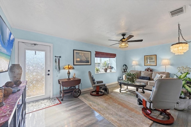 living room with hardwood / wood-style flooring and ceiling fan with notable chandelier