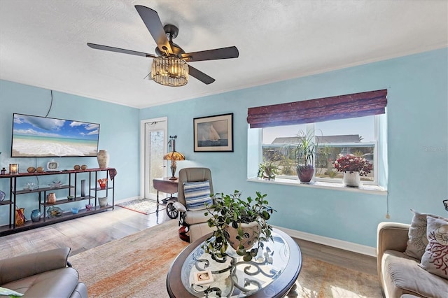 living room with ceiling fan, wood-type flooring, a textured ceiling, and ornamental molding