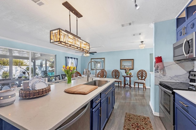 kitchen with hanging light fixtures, stainless steel appliances, sink, and blue cabinets