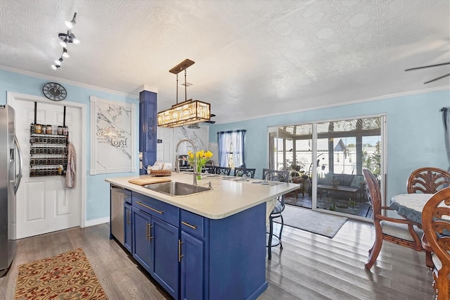 kitchen with pendant lighting, blue cabinets, sink, and a center island with sink