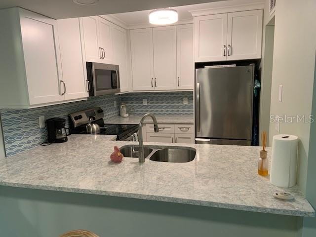 kitchen with light stone countertops, backsplash, stainless steel appliances, and a sink