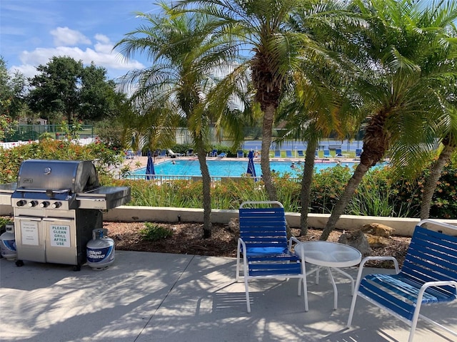 view of patio / terrace with a grill, a community pool, and fence