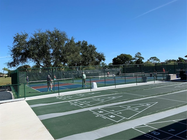 view of community with a tennis court and fence