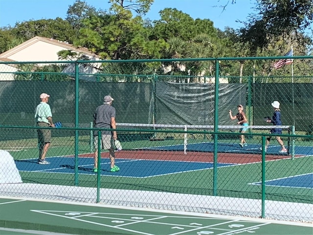 view of tennis court with community basketball court and fence