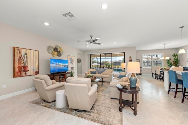 living room featuring a healthy amount of sunlight, ceiling fan with notable chandelier, and light tile patterned floors