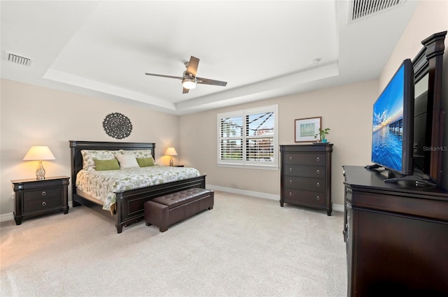 carpeted bedroom featuring a tray ceiling and ceiling fan