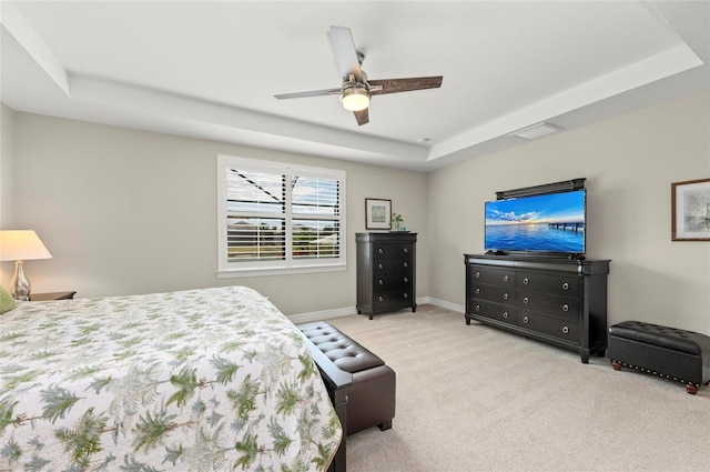 bedroom with a tray ceiling, light colored carpet, and ceiling fan