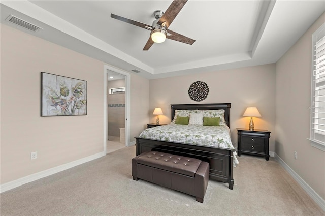 carpeted bedroom with connected bathroom, a raised ceiling, and ceiling fan