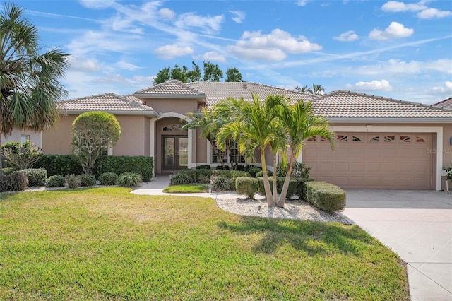 mediterranean / spanish-style house with a garage, a front lawn, and french doors