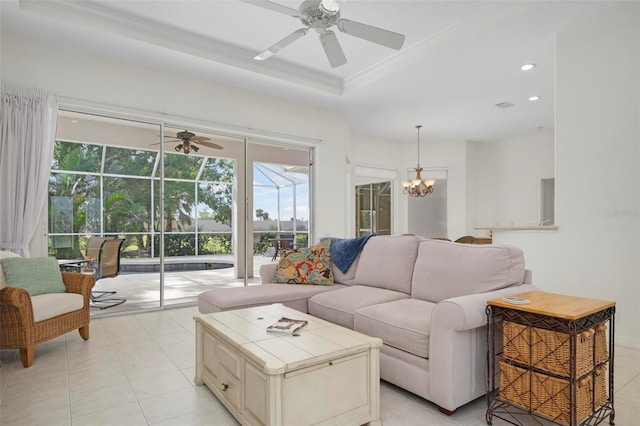 tiled living room featuring a tray ceiling and ceiling fan with notable chandelier